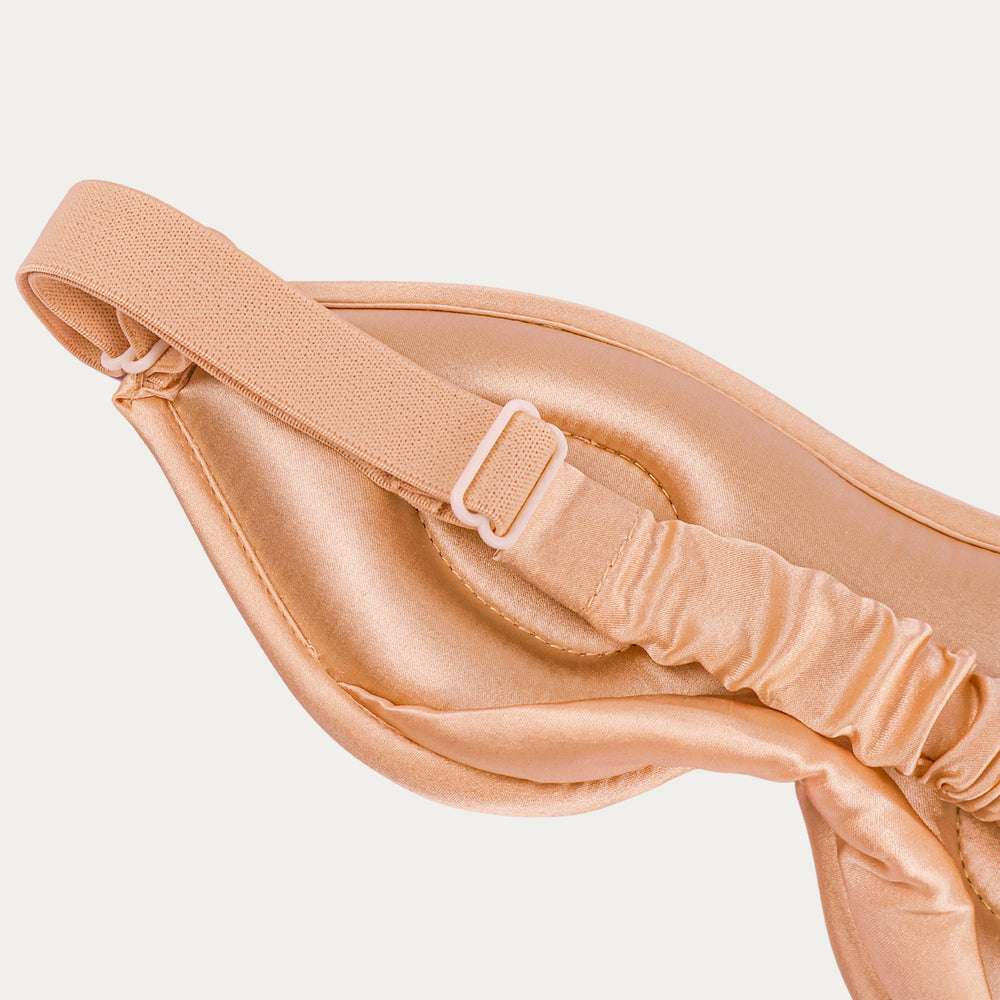 Beige satin eye mask on a light beige background

