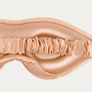Beige satin sleep mask on a light gray background

